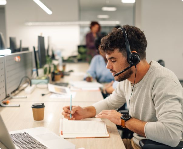 After hours answering service agent at call center desk with coffee and telephone answering headset