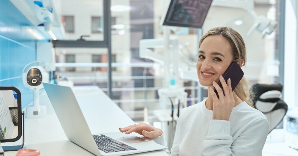 Nurse smiling sitting at a desk and talking on the phone