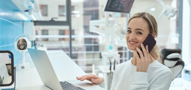 Nurse smiling sitting at a desk and talking on the phone