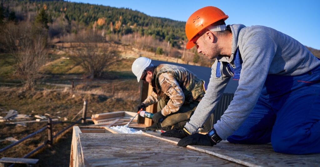 Roofing crew on a roof installing thermal insulation to protect from the elements.