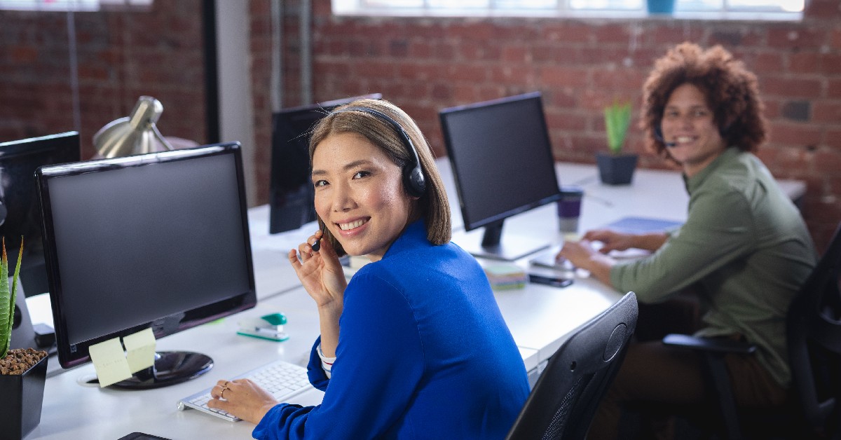 Call center workers taking calls in front of a desk with a computer.